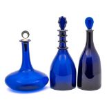 Three blue glass decanters: comprising a mallet shaped example with triple neck rim and faceted
