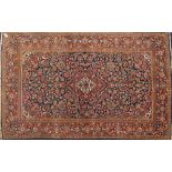 A Kashan rug:, the indigo cartouche field with a central rust shaped lozenge pole medallion,