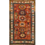 A Kazak rug:, the brick red field with a row of six octagonal and stellar medallions,