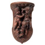 A carved wooden wall bracket: in the Italianate taste decorated with three cherubs within a foliate