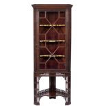 An Edwardian carved mahogany corner display cabinet on a stand:, with canted angles,