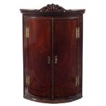 A mid 18th Century mahogany bow-fronted hanging corner cupboard:,