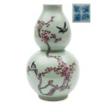 A Chinese famille rose double gourd vase: painted with birds and branches of pink blossom on a