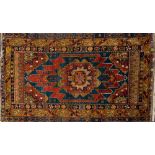 A Hamadan rug:, the indigo and brown serrated field with a central geometric medallion,