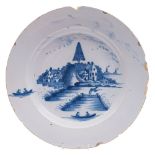 An English blue and white delftware charger: painted with a lake landscape scene,