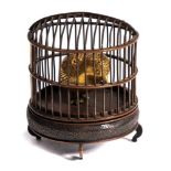 A Japanese bronze okimono: of a gilded bird in a cage, mounted on a circular stand, unsigned,