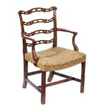 A George III carved mahogany ladderback elbow chair: the shaped and pierced splats with scroll