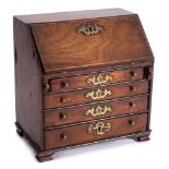 A George III period miniature mahogany writing bureau: the sloping hinged fall enclosing an