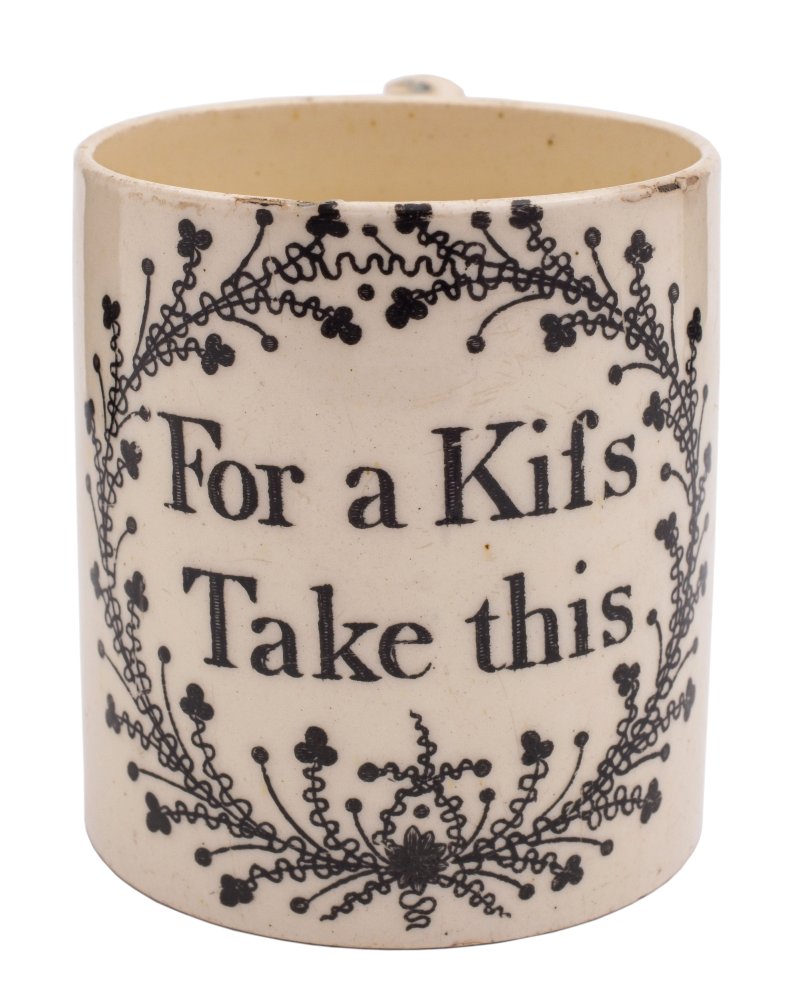 An English creamware small mug: printed in black 'For a Kifs/ Take this' within a foliate cartouche,