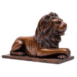 An early 19th Century carved padouk wood model of a recumbent lion: with crossed front paws on a