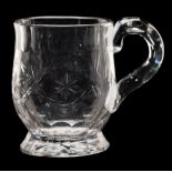 A small clear glass mug: of thistle shaped form with facet cut handle and slice cut rim and foot,