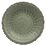 A Chinese Longquan celadon dish: the centre moulded with a floral roundel within a wide fluted