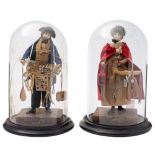 A pair of early 19th Century pedlar dolls: she in bonnet and red cloak, her wares include a lantern,