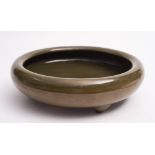 A Chinese tea-dust glazed tripod bowl: of squat circular form with rolled rim, 27cm diameter.