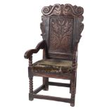A 17th Century carved oak open armchair:, the back with shaped top rail decorated with twin snakes,