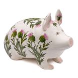 A Plichta pottery pig: modelled in seated position and decorated with flowering thistles,