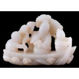A Chinese carved jade group: of three figures seated in a boat, pine trees in the background, 11cm.