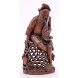 A Chinese bamboo carving of a fisherman: holding a carp and seated on a large basket,
