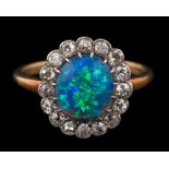 A black opal and diamond oval cluster ring: the central oval black opal approximately 10mm long x 8.