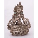 A small Tibetan silver Buddha: wearing ornate headdress and turquoise inlaid earrings,