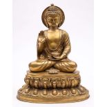 A large gilt brass figure of Buddha: seated crossed legged in traditional robes, on a lotus flower,