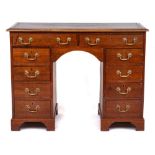 A mahogany rectangular kneehole desk:, the top inset with a panel of tooled leather,