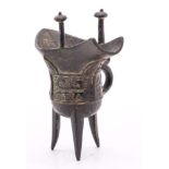 A small Chinese 'archaic' bronze wine vessel [Jue]: of conventional form cast with taotie masks on