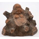 A Chinese Yixing figure of Budai: emerging from a large tree stump, 11cm. high [minor losses].