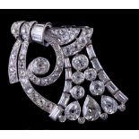 A platinum and diamond clip brooch: of openwork scroll design with round and pear-shaped old