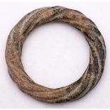 A Chinese calcified jade bangle: of archaic form, carved as a continuous twisted rope, 11cm.