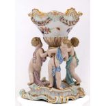 A Meissen porcelain group: modelled with three scantily clad putti supporting a large footed vase