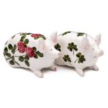 Two Bovey Tracey Wemyss pottery pigs: of small stature and in seated posture,