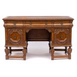 A similar oak kneehole writing desk: of canted design with a tooled leather inset moulded top,