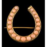 A late 19th Century gold and coral mounted horseshoe brooch: with graduated circular coral,