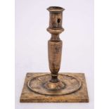 A 17th Century Continental brass candlestick: with plain cylindrical nozzle on a slender tapering