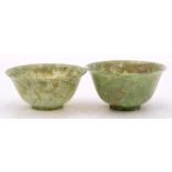 Two Chinese jadeite bowls: each with flared rim, the translucent celadon coloured stone with cream,
