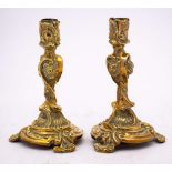 A pair of early 19th Century gilt brass candlesticks: in the rococo taste,