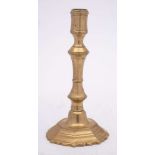An 18th Century French brass candlestick: the octagonal shaped nozzle on a knopped stem,
