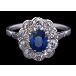 A sapphire and diamond oval cluster ring: the central, oval sapphire approximately 6.4mm long x 5.