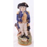 A Staffordshire character jug modelled as Admiral Lord Nelson: standing beside a cannon and holding