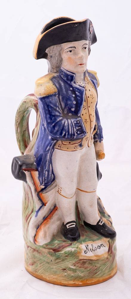 A Staffordshire character jug modelled as Admiral Lord Nelson: standing beside a cannon and holding - Image 2 of 3