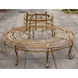 A wrought iron circular tree guard seat:, of slatted design on shaped scroll legs,