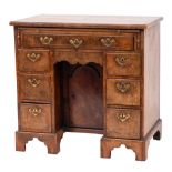 An early 18th Century walnut and feather banded kneehole desk: the wide crossbanded top with a