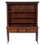 An 18th Century oak dresser:, the shelved superstructure with a moulded dentil cornice,