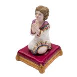 A Bloor Derby figure of a young girl at prayer: kneeling on a gilt and apricot tasselled burgundy