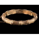 A 9ct gold bamboo-style bangle: with attached safety chain, approximately 16gms gross weight.