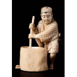 A Japanese carved ivory okimono: of a peasant pounding grain,