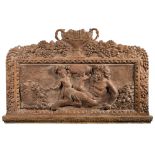 A limed and carved oak panel: decorated with Bacchus and two putti amongst wine jars and grapes,