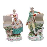 A pair of Derby figures of a gallant and lady: each with an open basket and a seated dog at their