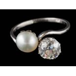 A pearl and diamond two-stone cross-over ring: the round old, brilliant-cut diamond approximately 6.